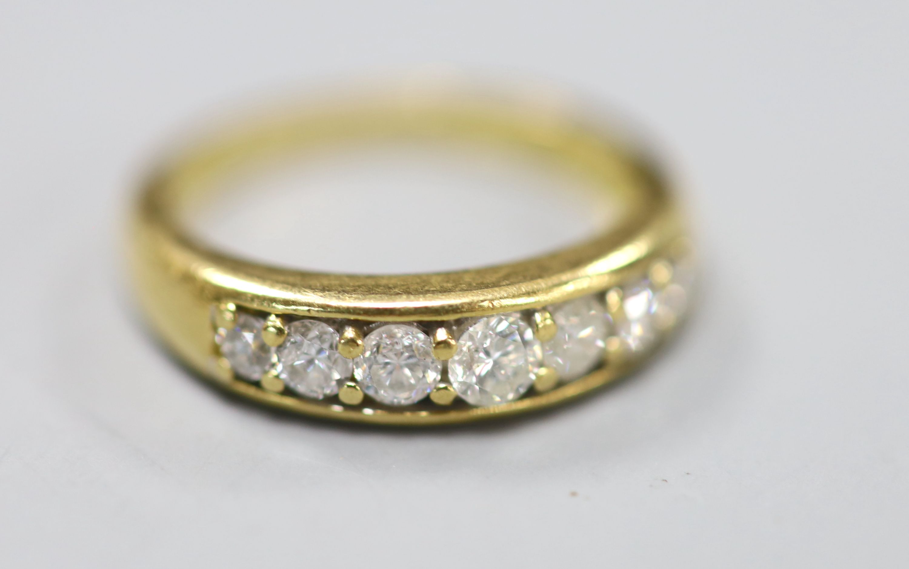 A modern 18ct gold and channel set seven stone diamond set half hoop ring, size K, gross 4.2 grams,